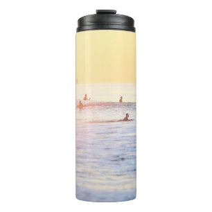 Mensen die op het strand surfen thermosbeker