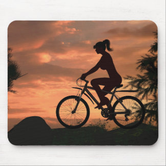 Mooie meid die op haar fiets rijdt bij zonsonderga muismat