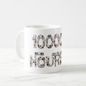 Mug 10000 hours with an overlay of paint brushes.  (Devant gauche)