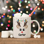 Mug Cute Reindeer Garçon Feux de Noël Nom personnalisé<br><div class="desc">Un café de Noël mignon ou une tasse de cacao chaud est illustré d'un visage de garçon de rennes de Rudolph sucré avec un nez rouge brillant, des cils et des bois. Il est habillé d'un brin d'ampoules colorées de Noël et entouré de flocons de neige gris clair. Personnalisez cette...</div>