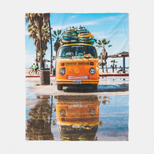 Oranje bestelwagen met surfplank bovenaan fleece deken