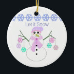 Ornement Rond En Céramique Snowman avec Flèches de neige<br><div class="desc">Un mignon bonhomme de neige avec des branches pour les bras,  tenant des ornements colorés de flocon de neige. Une bordure de flocons bleus accentue le sommet. Le dicton 'Let it Snow' peut être changé comme souhaité.</div>