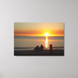 Paar zit op strand op Sunset Canvas print