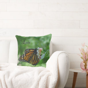 Papillon Monarch en vol sur un oreiller fleuri