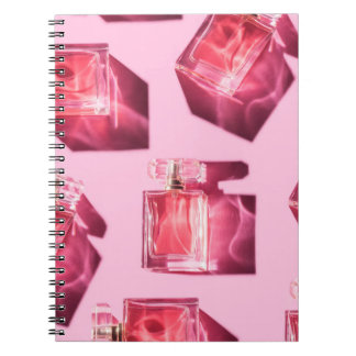 Parfumflessen, roze achtergrond, flatlay notitieboek