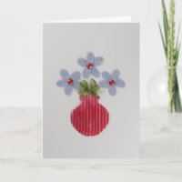 Pas Blauwe bloemen in rode vaas aan