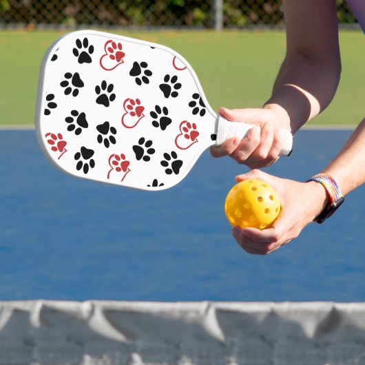 Patroon van poten, zwarte poten, rode poten, harte pickleball paddle (Insitu)