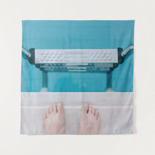 Persoon die op de zwembadladder staat wandkleed