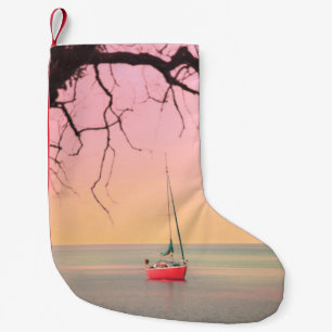 PETITE CHAUSSETTE DE NOËL BATEAU ROUGE SUR LA PLAGE PENDANT LE COUCHER DE SO