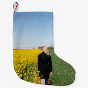 Petite Chaussette De Noël Femme en manteau noir debout sur un terrain d'herb