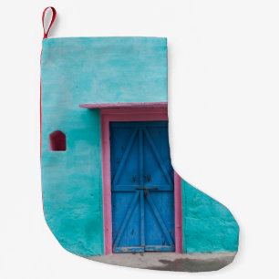 PETITE CHAUSSETTE DE NOËL PORTE EN BOIS ROUGE SUR MUR EN BÉTON BLEU