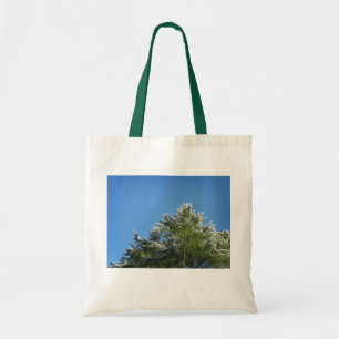 Pijnboom met sneeuwklemmen op blauwe hemel tote bag