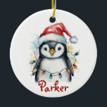 Pingouin Ornement de Noël personnalisé<br><div class="desc">Célébrez la saison avec cet adorable ornement de Noël personnalisé de pingouins ! Doté d’un pingouin à l’aquarelle portant un chapeau de Père Noël et enveloppé de lumières de fête colorées, ce garde-robe en céramique inclut le nom de votre enfant dans un script rouge festif. Cet ornement, qui s’ajoute parfaitement...</div>