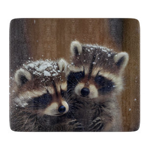 Planche À Découper Bébé Raccoons se blottit dans le verre de neige