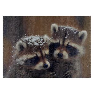 Planche À Découper Bébé Raccoons se blottit dans le verre de neige