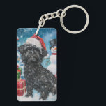 Porte-clés Affenpinscher Winter Wonderland Christmas Joie<br><div class="desc">Ce design festif reflète l'esprit joyeux de la période des fêtes, avec un adorable petit portant un chapeau de Père Noël. Le chien est niché dans un pays des merveilles hivernales, avec un bonhomme de neige, un sapin de Noël décoré et des cadeaux joliment emballés. Les flocons de neige tombent...</div>
