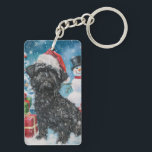 Porte-clés Affenpinscher Winter Wonderland Christmas Joie<br><div class="desc">Ce design festif reflète l'esprit joyeux de la période des fêtes, avec un adorable petit portant un chapeau de Père Noël. Le chien est niché dans un pays des merveilles hivernales, avec un bonhomme de neige, un sapin de Noël décoré et des cadeaux joliment emballés. Les flocons de neige tombent...</div>