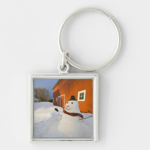 Porte-clés Bonhomme de neige devant la grange rouge en
