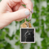 Porte-clés Chat noir sur le fond noir, plan rapproché (main)
