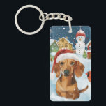 Porte-clés Dachshund Winter Wonderland Christmas Joy<br><div class="desc">Ce design festif reflète l'esprit joyeux de la période des fêtes, avec un adorable petit portant un chapeau de Père Noël. Le chien est niché dans un pays des merveilles hivernales, avec un bonhomme de neige, un sapin de Noël décoré et des cadeaux joliment emballés. Les flocons de neige tombent...</div>