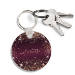 Porte-clés Script de nom de parties scintillant d'or rose de<br><div class="desc">Une couleur arrière - plan à l'aspect faux métallique bordeaux. Décoré avec de la poussière de parties scintillant en faux or rose. Personnalisez et ajoutez un nom. Le nom est écrit avec un script de style moderne écrit à la main avec des swashes. Pour que les swashes ne suppriment que...</div>