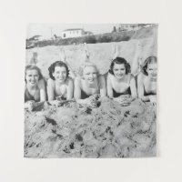 Portret of five young women lying on the beach an