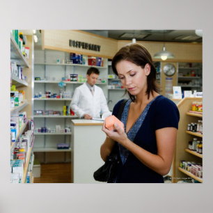 Poster Jeune femme qui regarde la médecine en pharmacie,