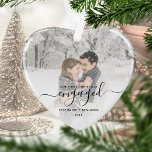 Premier Noël Engagé Photo Black Script Coeur<br><div class="desc">Commémorez votre fiançailles avec ce magnifique ornement en forme de coeur. Le texte noir indique "Notre premier Noël engagé", avec le mot "engagé" dans un élégant script d'écriture manuscrite avec des fioritures avant et après. Remplacez l'exemple d'image par votre photo préférée, et ajoutez vos noms et l'année. Un filtre en...</div>