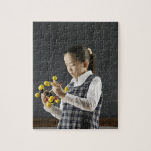 Puzzle Fille asiatique regardant le modèle de molécule