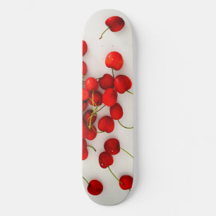 Rode kersen in natuurlijk licht liggen op wit skateboard