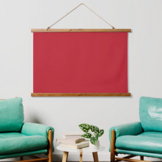 Rode, roze en oranje kledingstukken hangen naast e hangend wandkleed