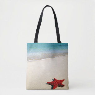 Rode zeester op witte zandband tote bag