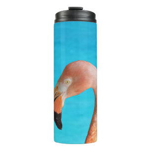 Roze flamingo gezicht tegen blauw water op een thermosbeker