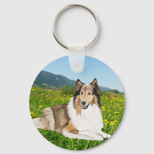 Ruw Collie tegen een bekerwei. Sleutelhanger