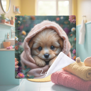 Schattig, klein, pluizig puppy omringd door bloeme washandje