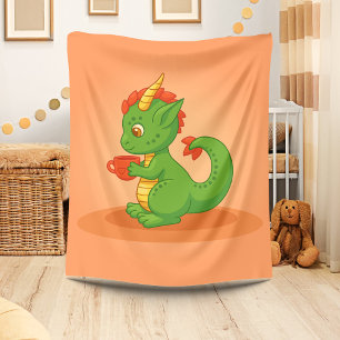 Schattige baby-draak houdt kopje vast op oranje fleece deken