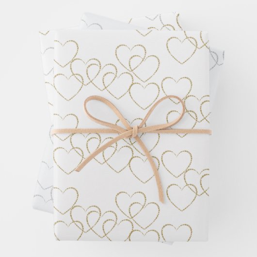 Schattigee gouden en zilveren hart charmes op wit inpakpapier vel (In situ)