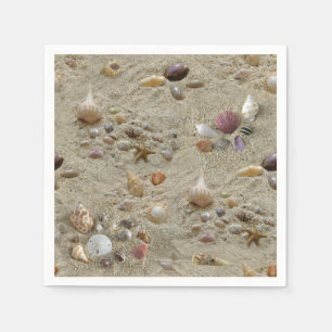 Schelpjes genesteld in het zand op het strand servet