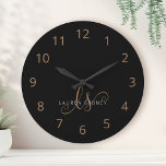Script féminin Black Gold moderne Monogramme<br><div class="desc">Script Feminine Noir Moderne Monogrammé Grande Horloge. Personnalisez facilement cette grande horloge moderne et élégante avec votre monogramme et votre nom personnalisés.</div>
