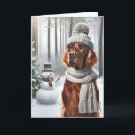 Setter irlandais de Noël avec Snowman<br><div class="desc">Un chien portant un casquette tricoté gris et une écharpe se tient dans une forêt enneigée à côté d'un bonhomme de neige pour Noël</div>