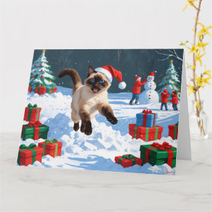 Siamees kat loopt in de sneeuw met kerstmuts kaart