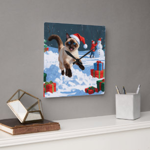 Siamees kat loopt in de sneeuw met kerstmuts vierkante klok