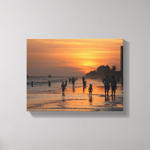 Silhouet mensen op het strand bij zonsondergang canvas afdruk