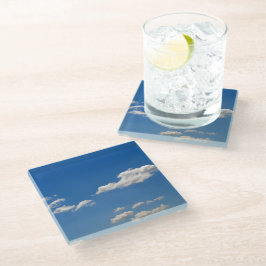 Sky is blauw en witte wolken gaan langs glazen onderzetter