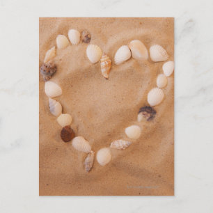 Sluiten van de hartvorm van schelpen op zand briefkaart