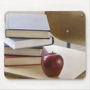 Stapel boeken, appel en schoolbureau muismat