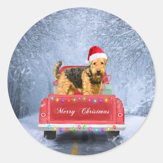 Sticker Rond Airedale Terrier Chien en Neige assis à Noël (Devant)