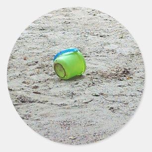 Sticker Rond Bouche verte perdue dans le sable sur la plage d'é