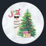 Sticker Rond Cool Christmas Llama | Joy Typography | Réserver<br><div class="desc">Un autocollant avec une drôle d'illustration. Un mignon lama portant des lunettes de soleil noires et un chapeau de santa rouge. Derrière un sapin de Noël avec des cadeaux festifs. Le mot Joy écrit au-dessus de sa tête dans une police de vacances colorée. Arrière - plan de livre d'argent. Design...</div>