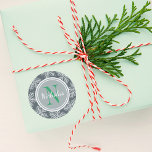 Sticker Rond Green Holiday Monogram Snowflake Border<br><div class="desc">Custom holiday sticker design features a border of white snowflakes with round silver / gray monogram frame. Personalize the emerald green letter initial and white script writing for your last name. The slate blue / gray background can be customized.</div>
